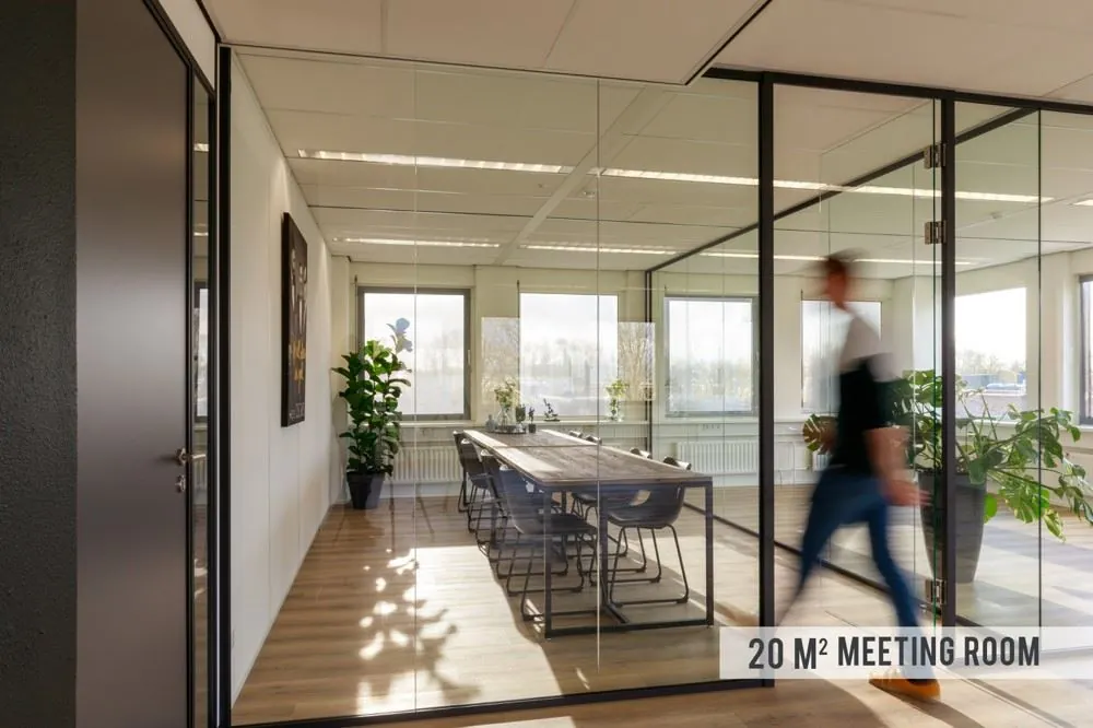 Moderne vergaderruimte van 20 m² met glazen wanden, houten vloer en strakke inrichting in een kantoorpand aan de Baarnsche Dijk.